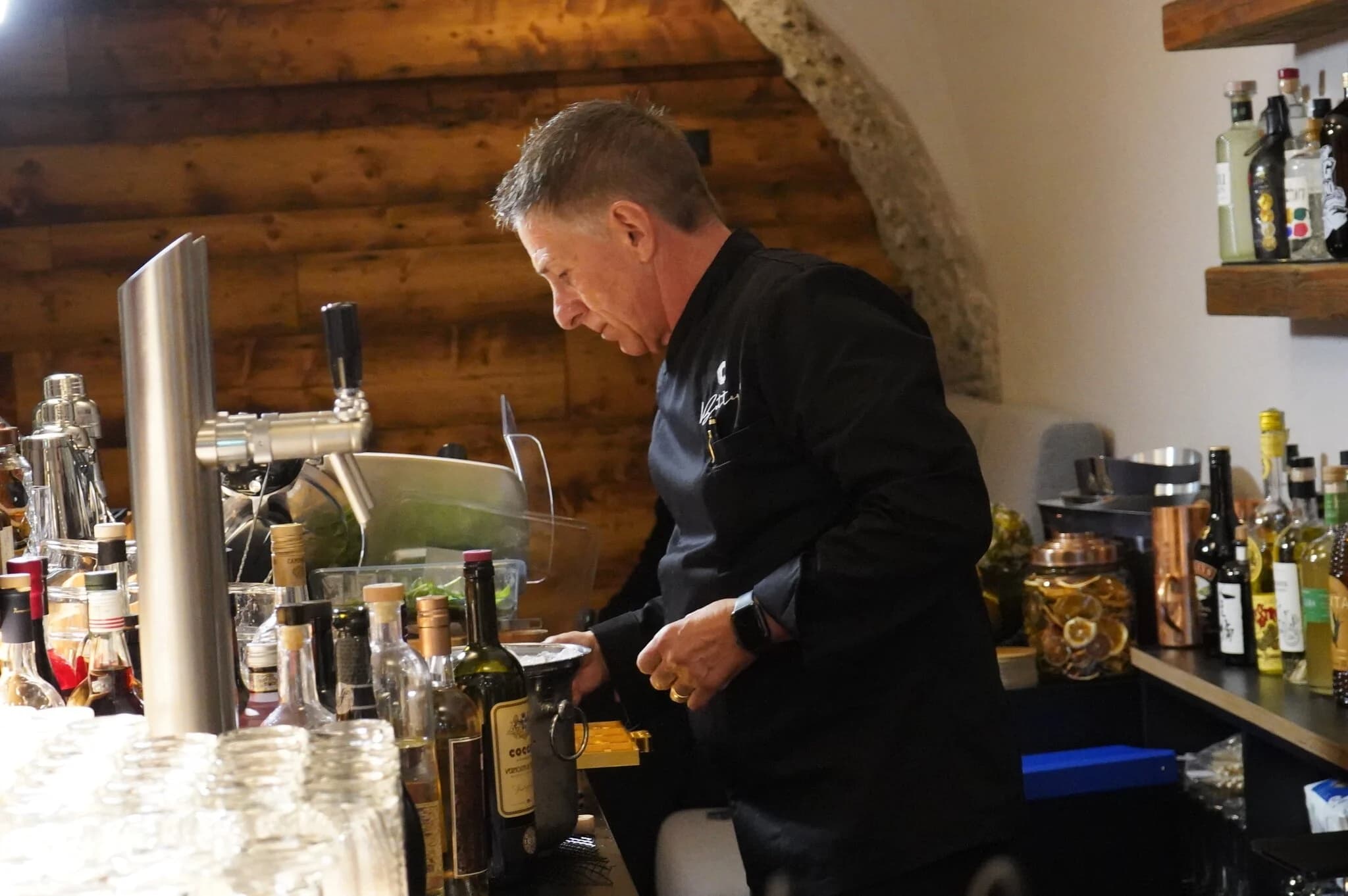 Massimiliano bei der Arbeit an der Bar, im Hintergrund Holzwand und Gewölbe
